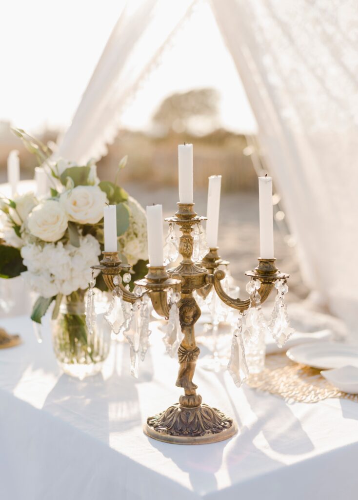 A luxurious outdoor wedding table adorned with white flowers and elegant candlesticks.