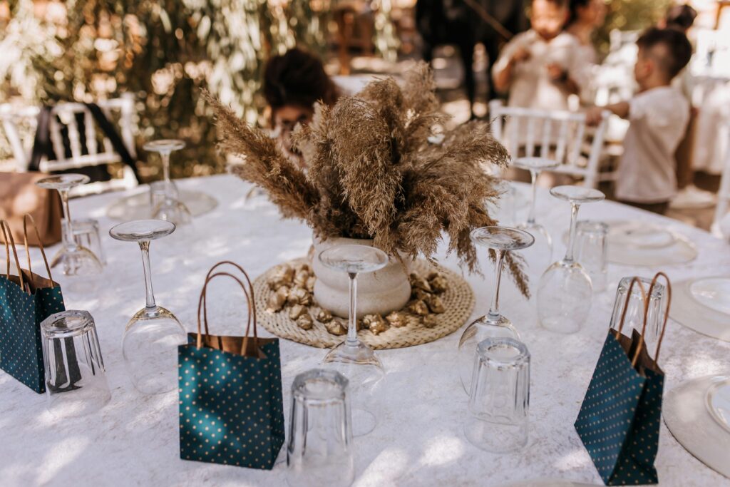 An elegant outdoor table setting featuring dry floral centerpiece and gift bags for a charming celebration.